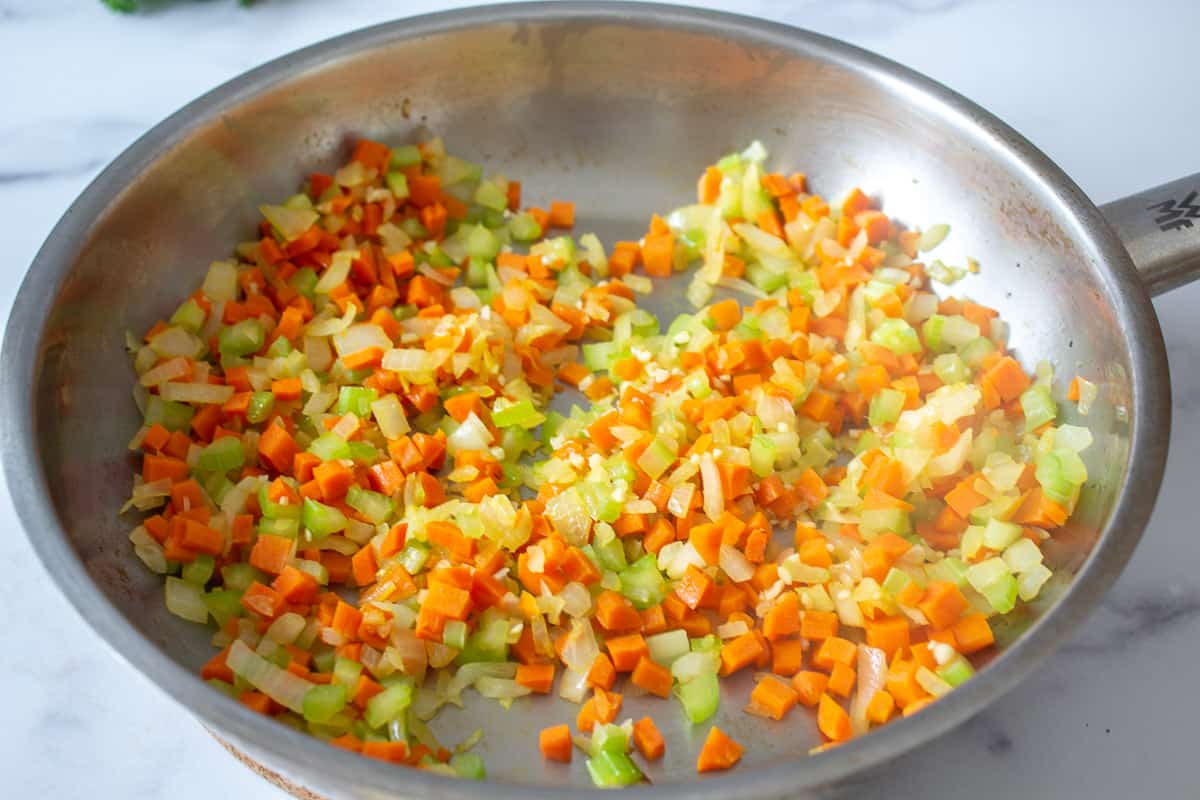 Cooked onions, carrots and celery in a pan.