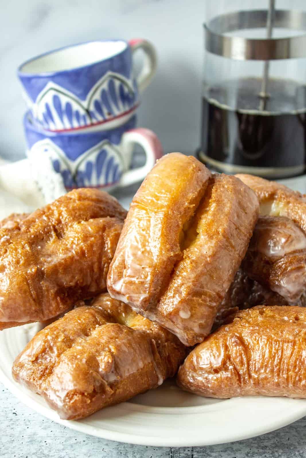 Glazed bars  on a white plate with coffee and cups in the background.