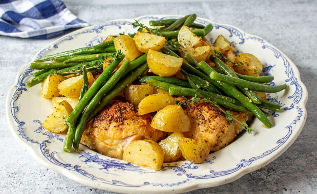 A blue and white plate filled with chicken, potatoes and green beans.