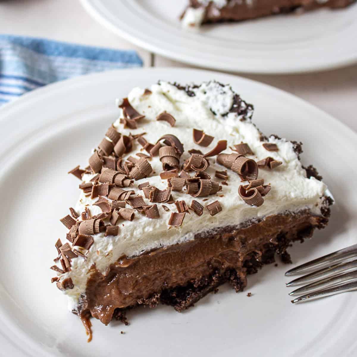 A slice of chocolate pie topped with whipped cream and chocolate shavings.