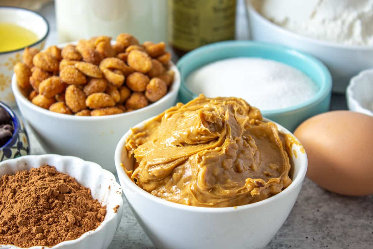 Small bowls filled with peanut butter, nuts, cocoa powder and other ingredients.