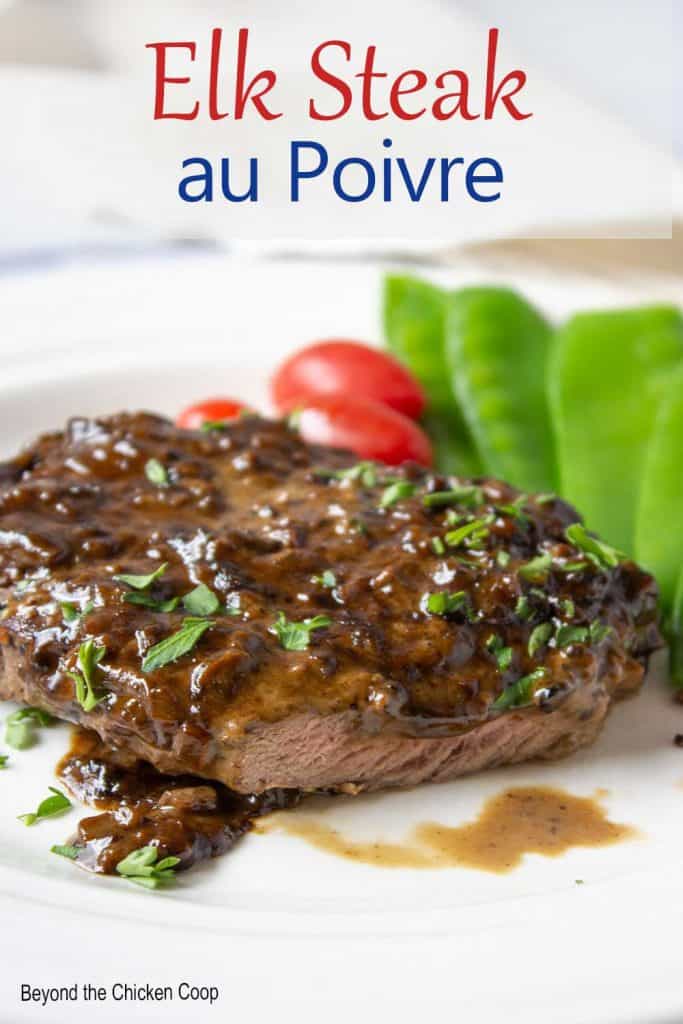 A steak covered with a brown sauce and chipped parsley.