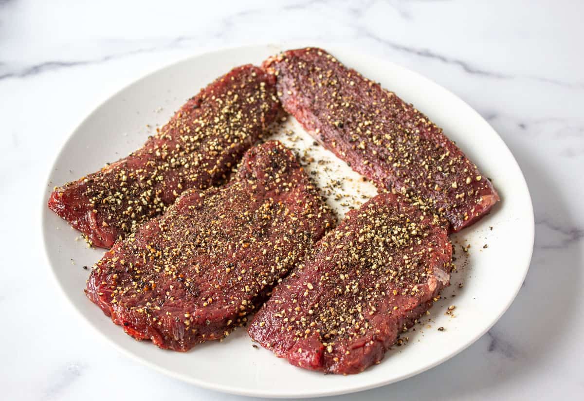 Steaks covered with crushed pepper.