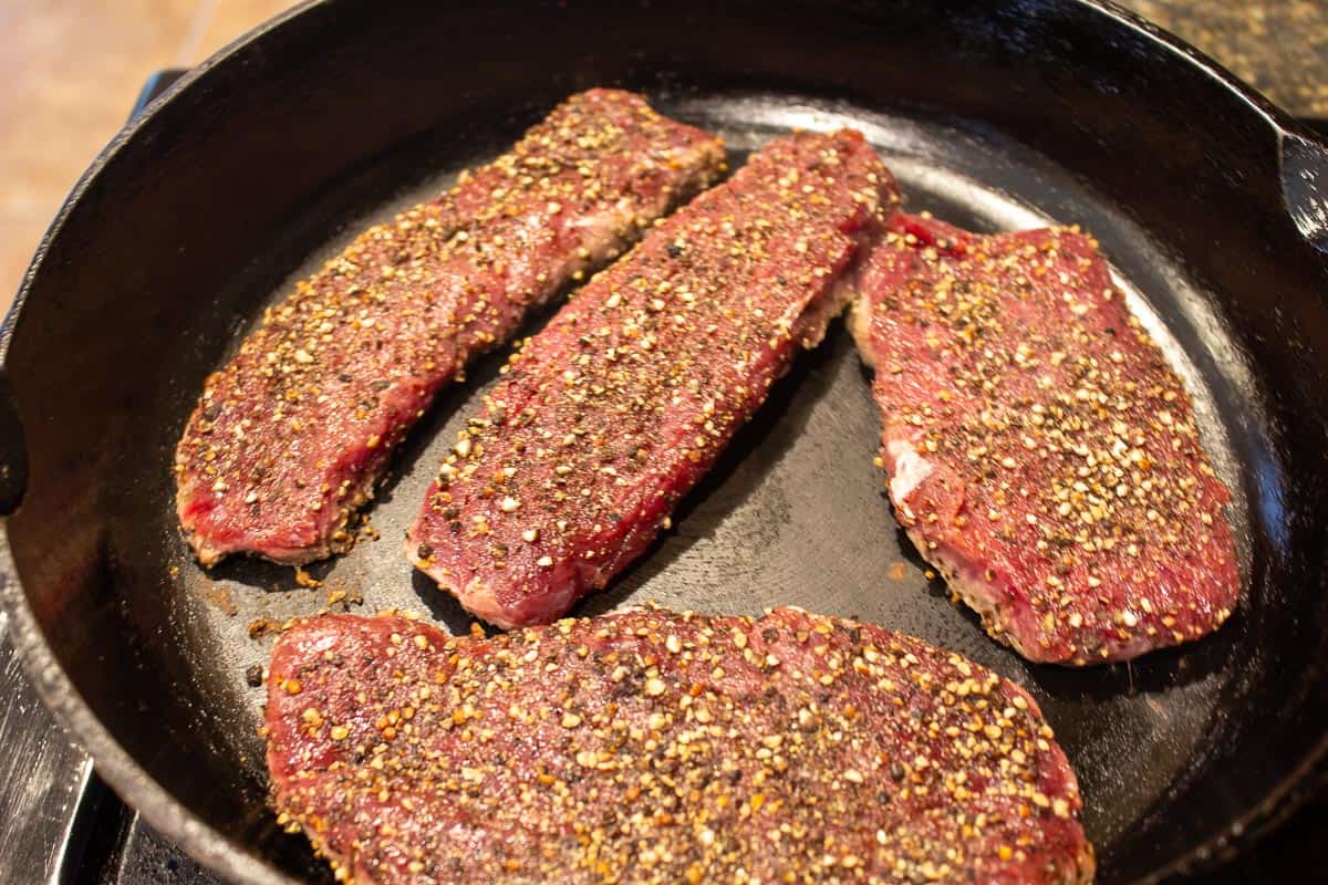 Elk steaks in a black cast iron pan.