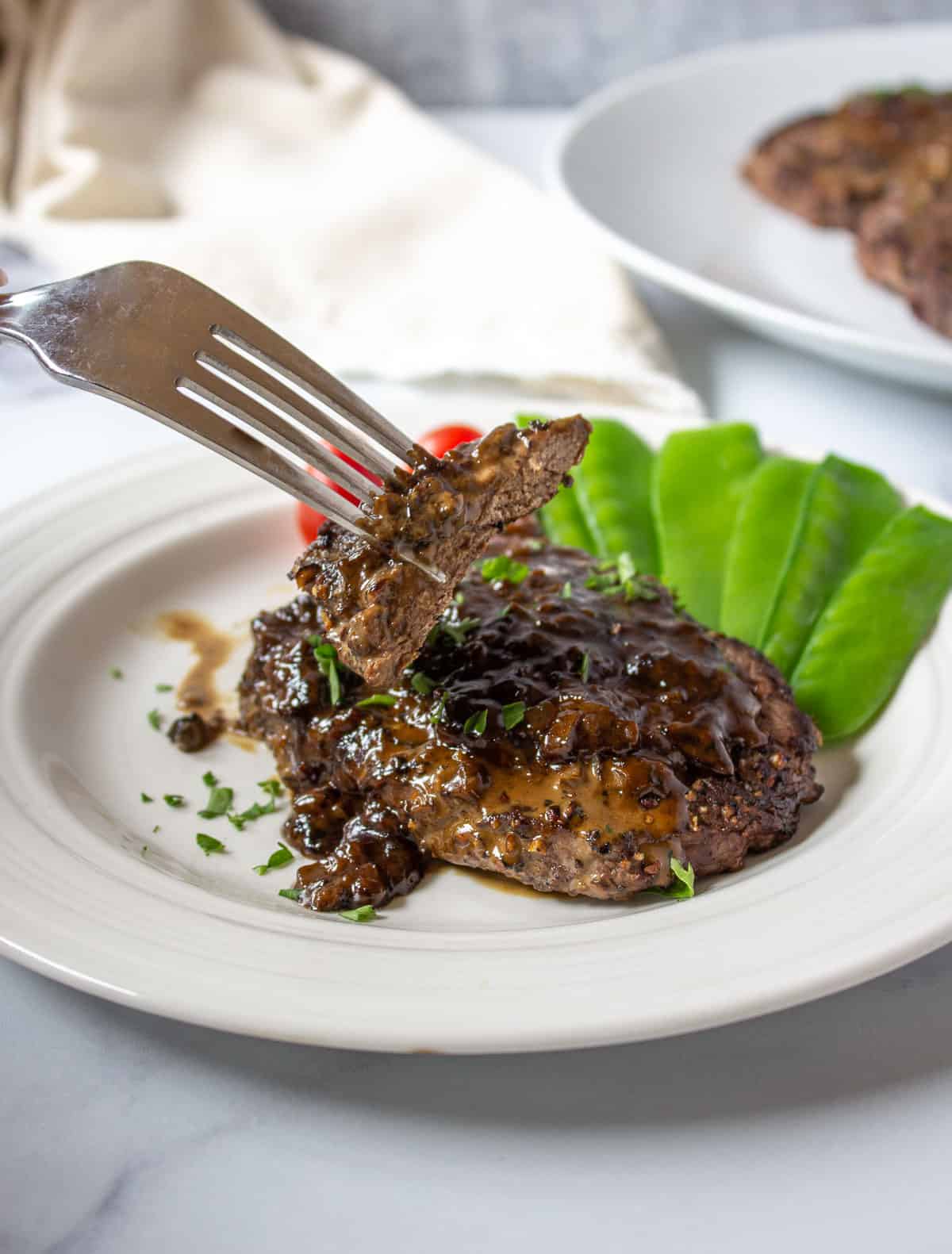 A slice of elk steak on a fork.