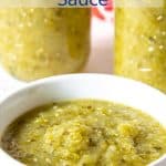 A green sauce in a white bowl with glass jars filled with the sauce behind the bowl.