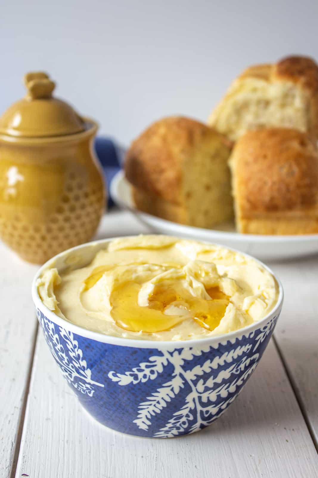 A small blue and white bowl filled with whipped butter and topped with honey.