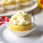 A lemon cupcake topped with a swirl of frosting on a white plate.