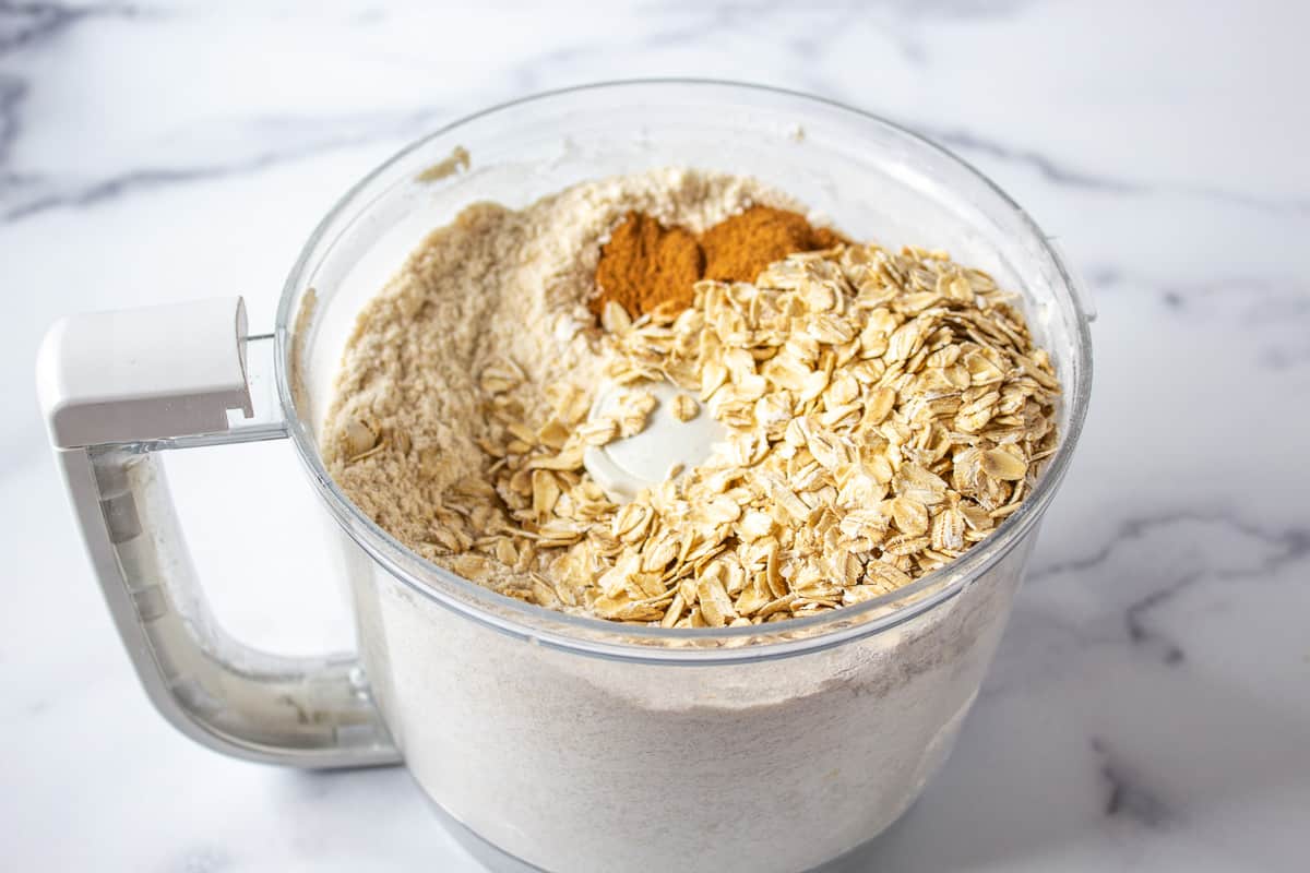 Oatmeal added to a food processor bowl.