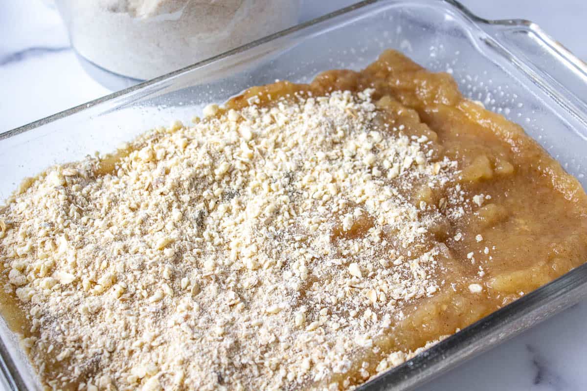 Applesauce topped with a crumbly mixture in a glass baking dish.