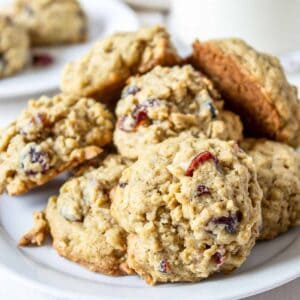 A plate filled with a stack of oatmeal cookies with cranberries.