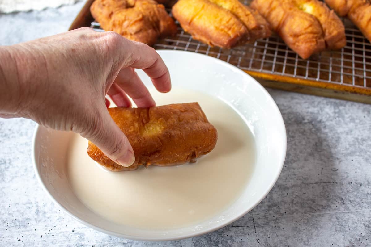 A bar being dipped into a bowl of white glaze.