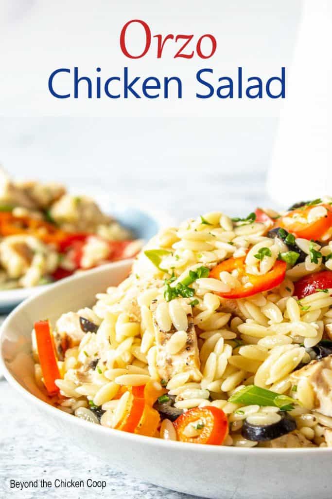 Orzo pasta with chunks of chicken and slices of bell pepper in a bowl.