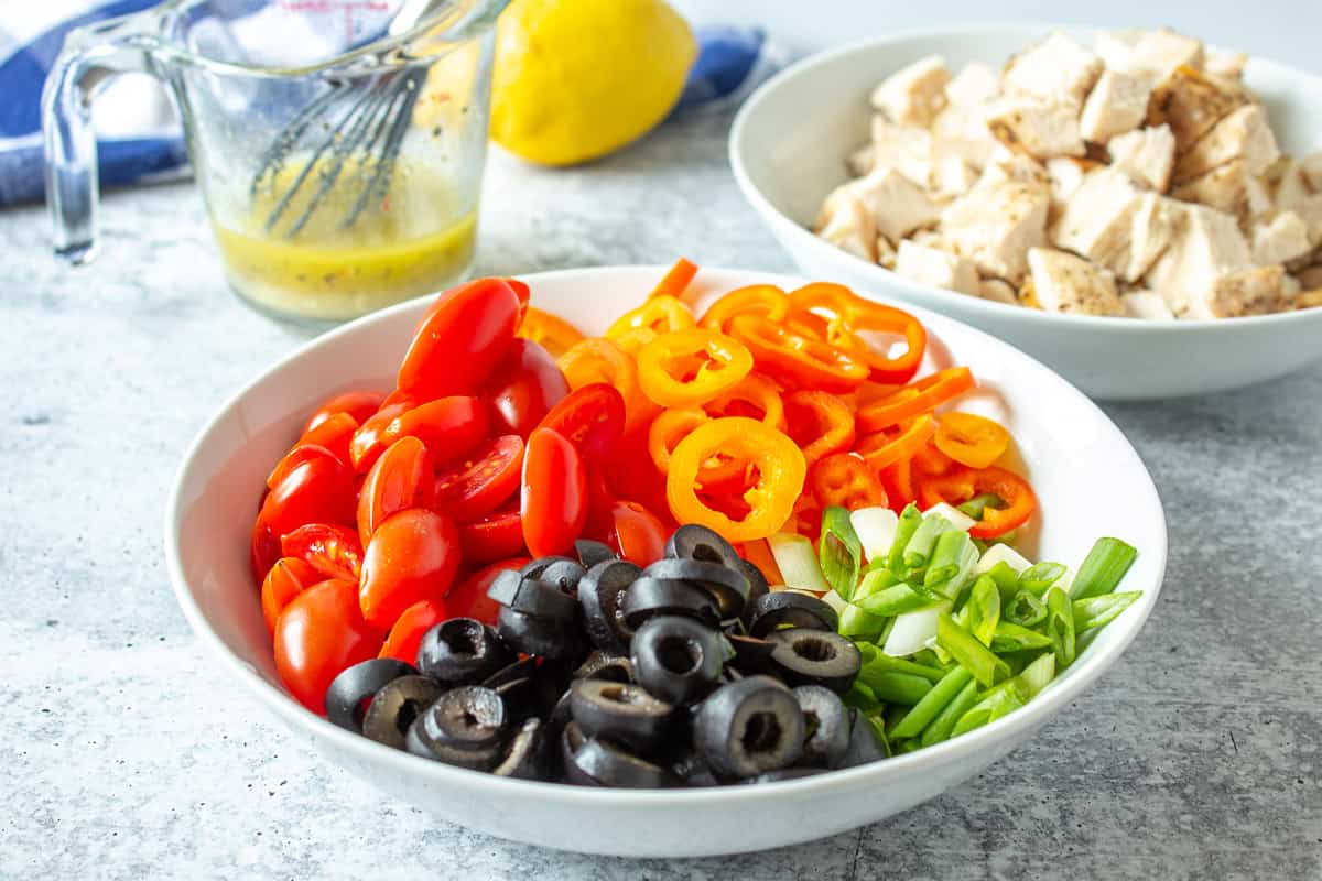 Fresh cut peppers, tomatoes and onions in a white bowl.