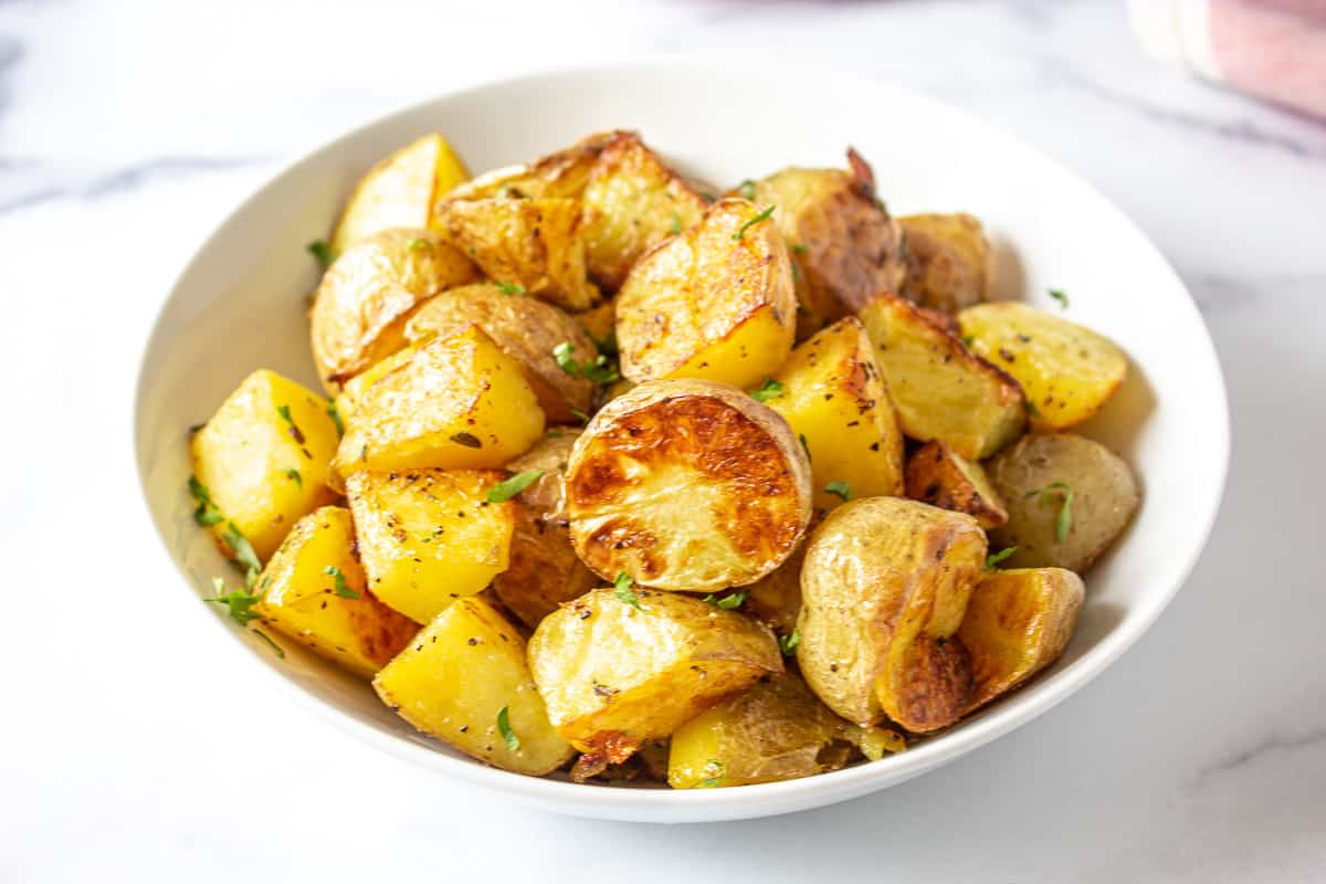 A white bowl filled with oven roasted yukon potatoes.