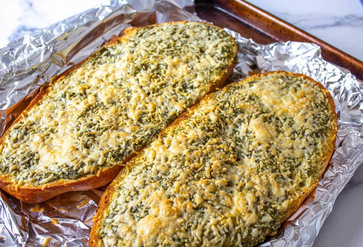 Cheesy garlic bread on top of foil on a baking sheet.