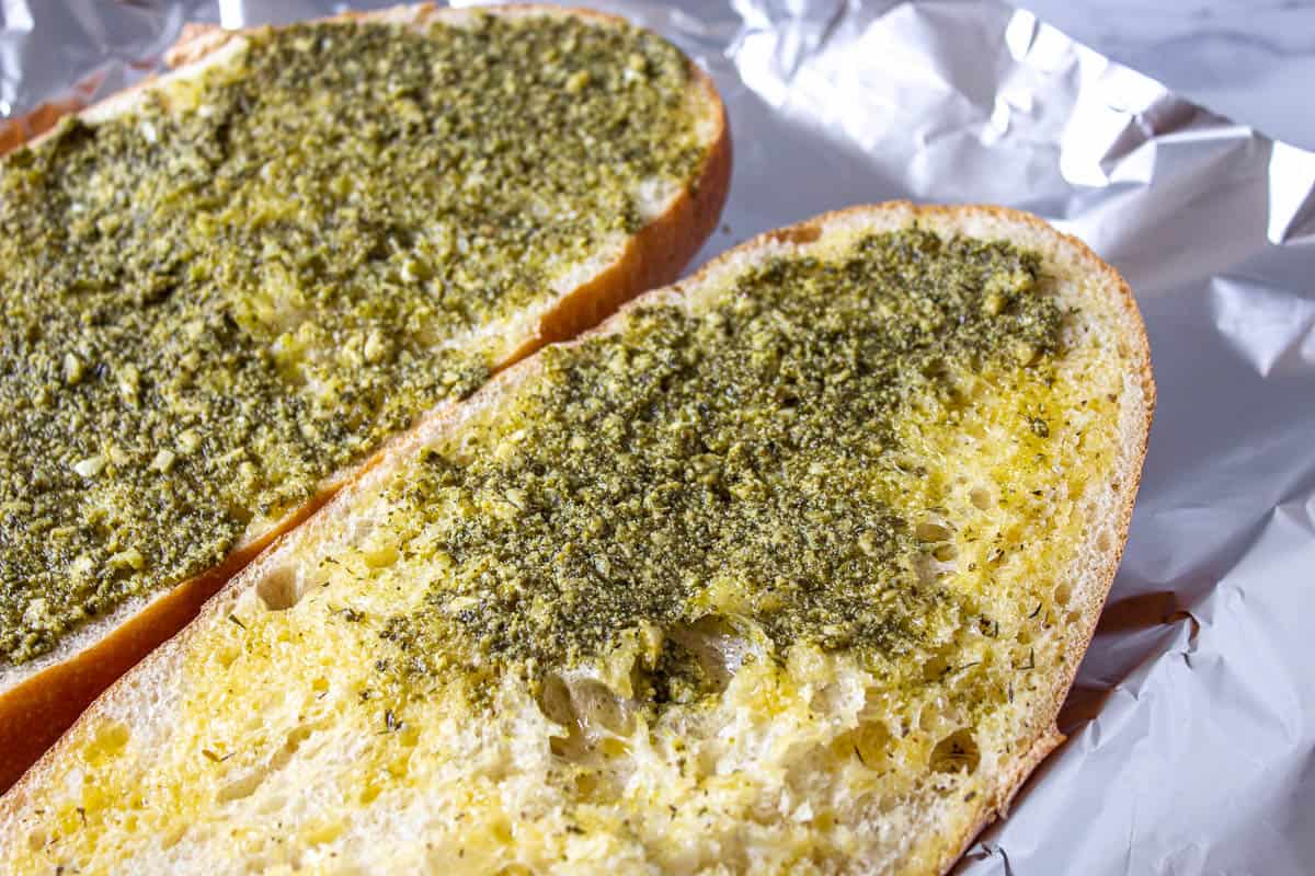 Sliced french bread topped with butter and pesto.