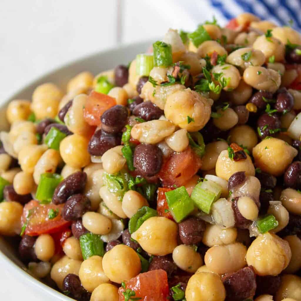 Black beans, and garbanzo beans mixed with tomatoes and green onions in a bowl.