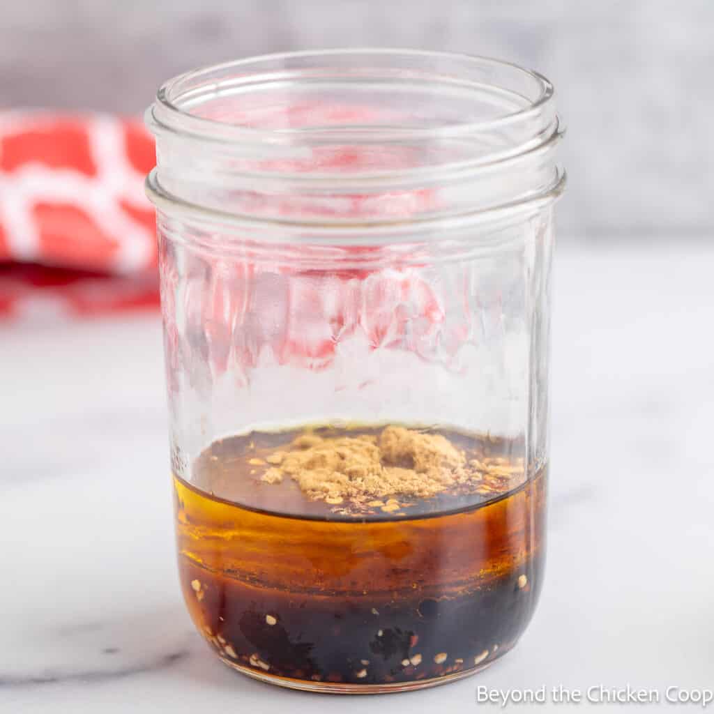 Placing salad dressing ingredients in a glass jar. 