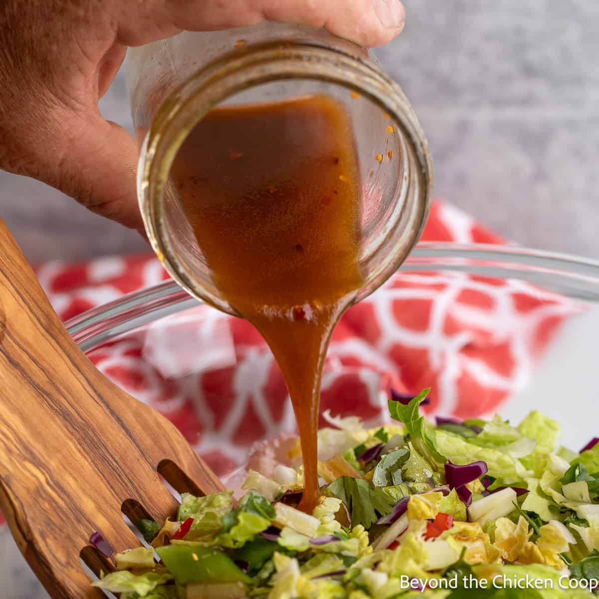 Pouring a salad dressing over a salad.