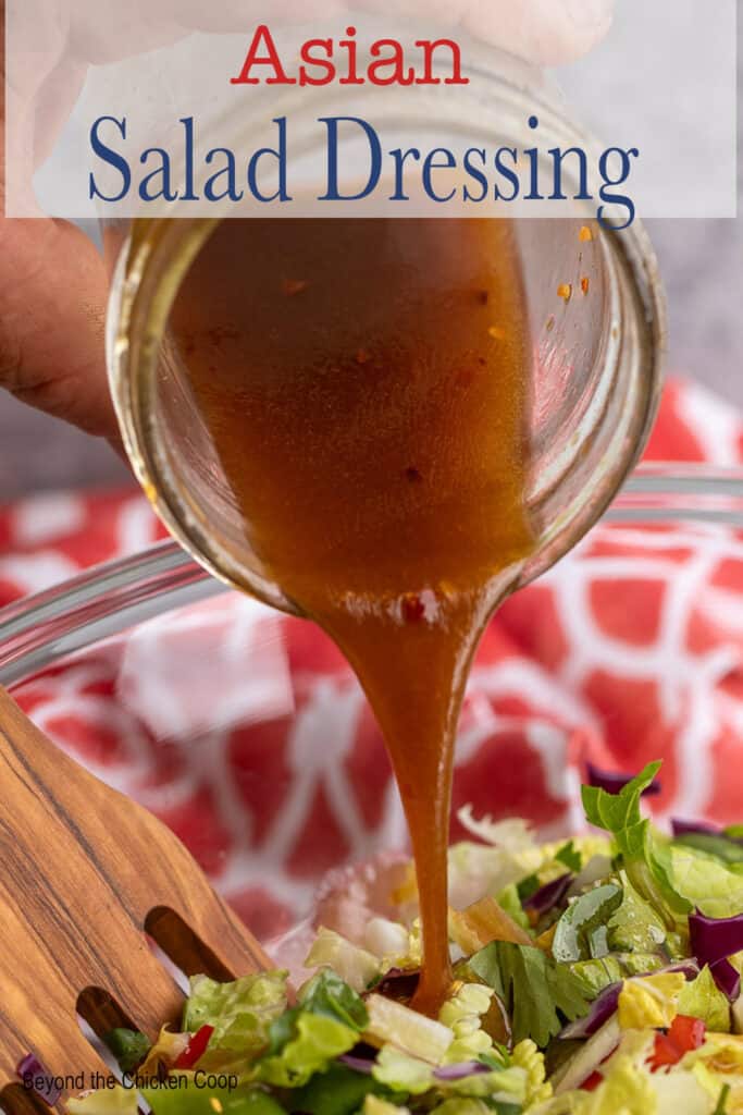 Salad dressing being poured over a green salad.