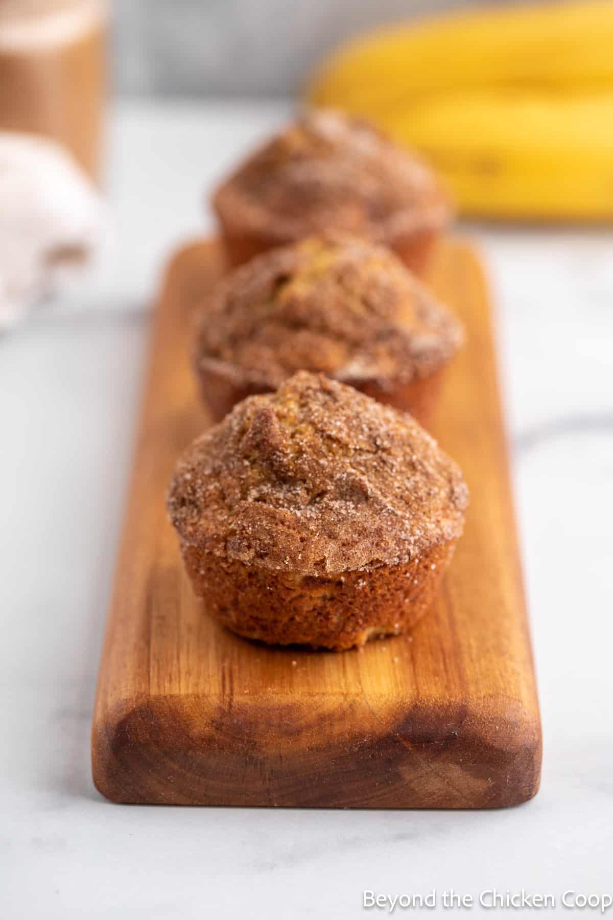 Banana cinnamon muffins in a line on a wooden board. 
