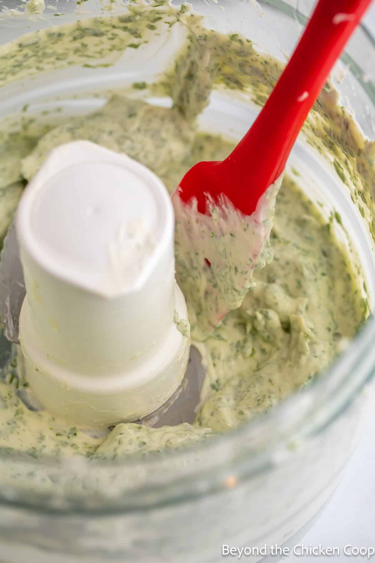 Basil mayo in a food processor with a red spatula. 