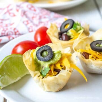 Crispy mini cups filled with black beans, cheese and guacamole and topped with a black olive.