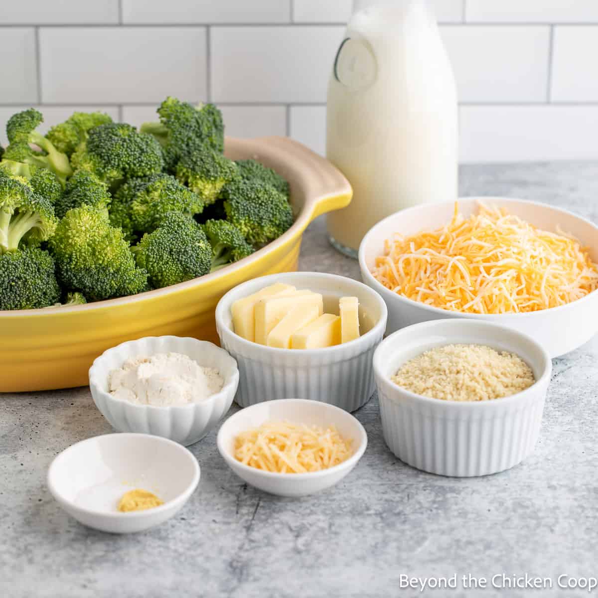 Broccoli, cheese, milk and other ingredients in small bowls. 