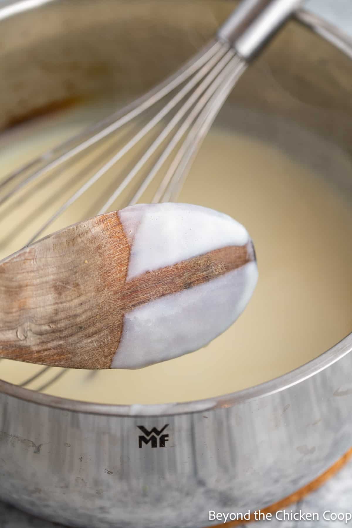 Thickened sauce on the back of a wooden spoon. 