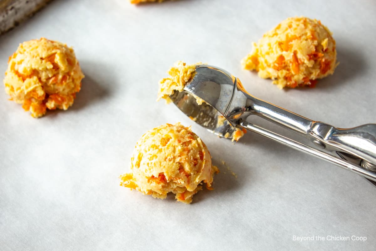 A cookie scoop placing balls of dough on a cookie sheet.