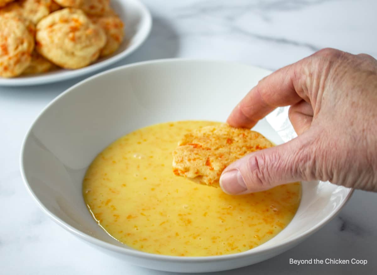 Dipping a cookie into an orange glaze.