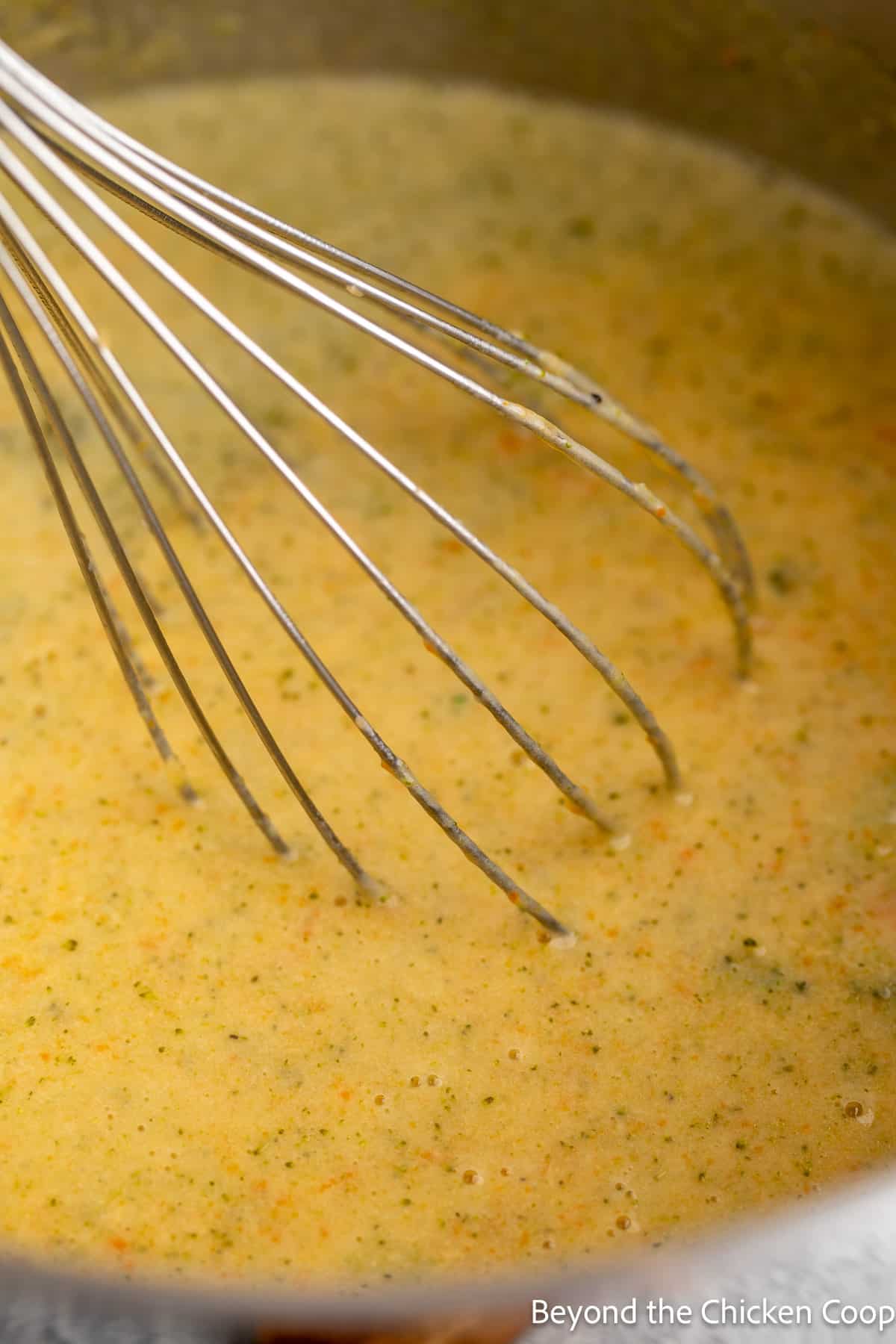 Pureed soup in a pot with a whisk.