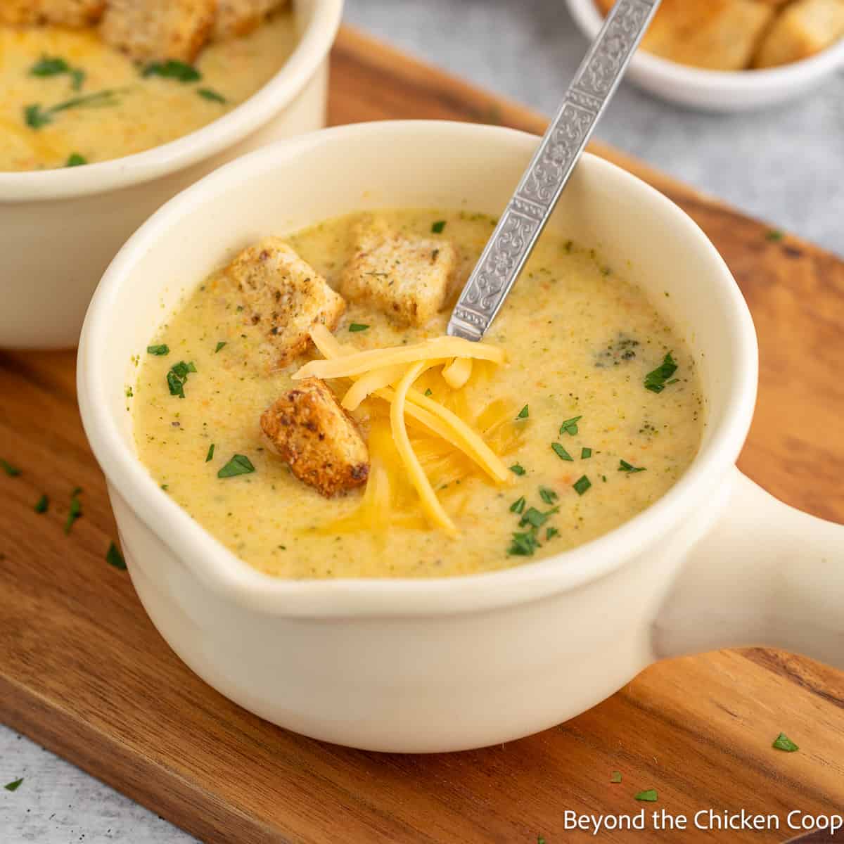 A bowl filled with broccoli soup topped with shredded cheese and croutons. 