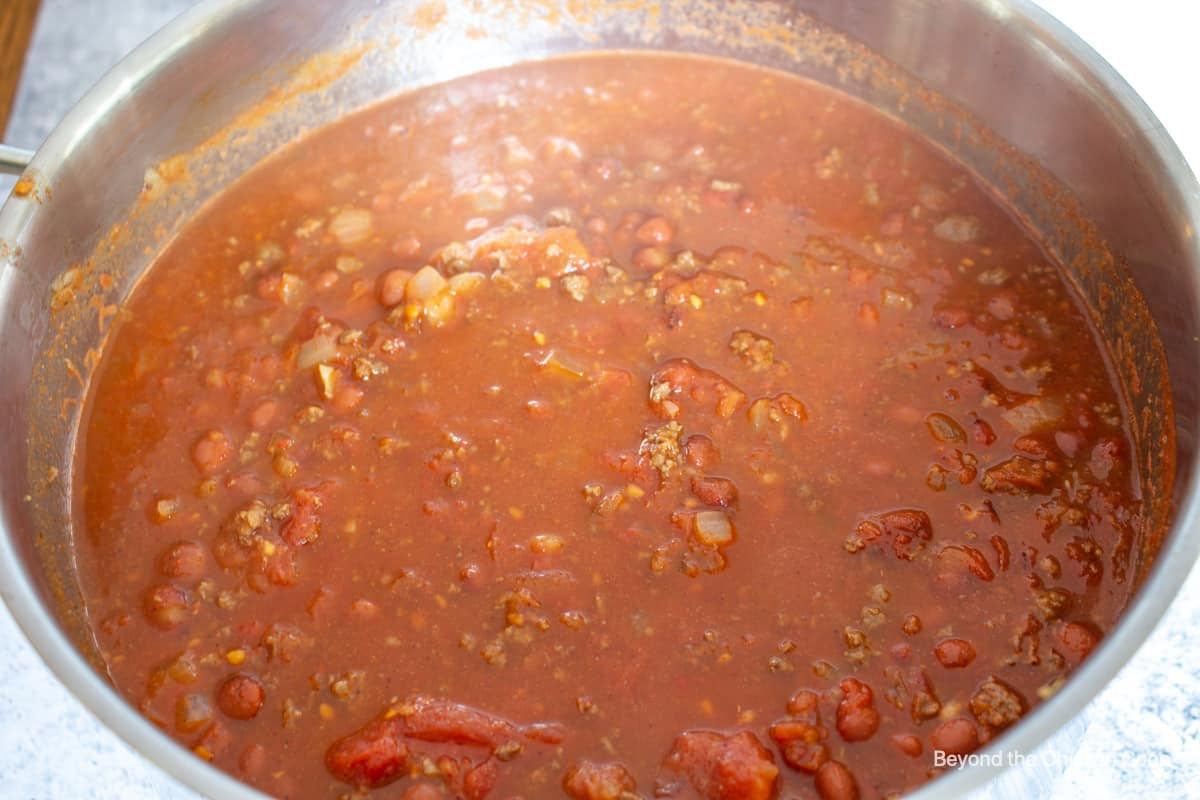 A large pot of simmering chili with meat and beans.