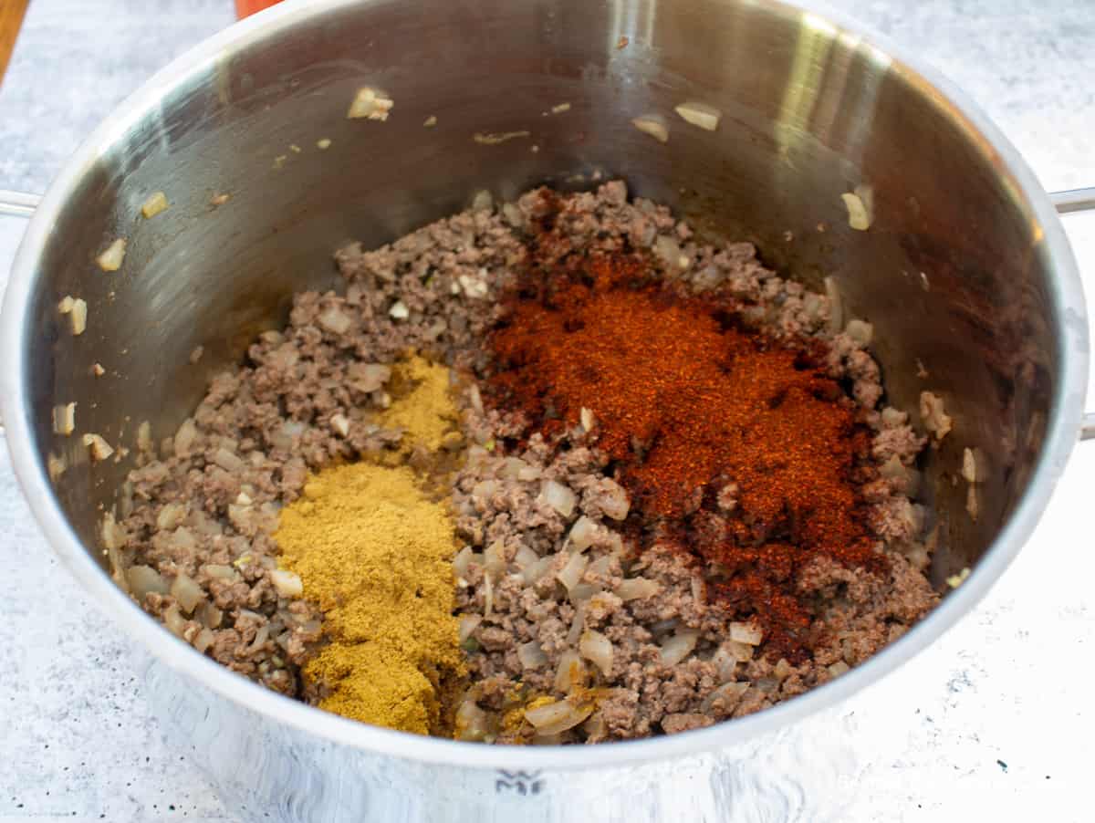 Ground chili powder and ground cumin added to cooked burger.