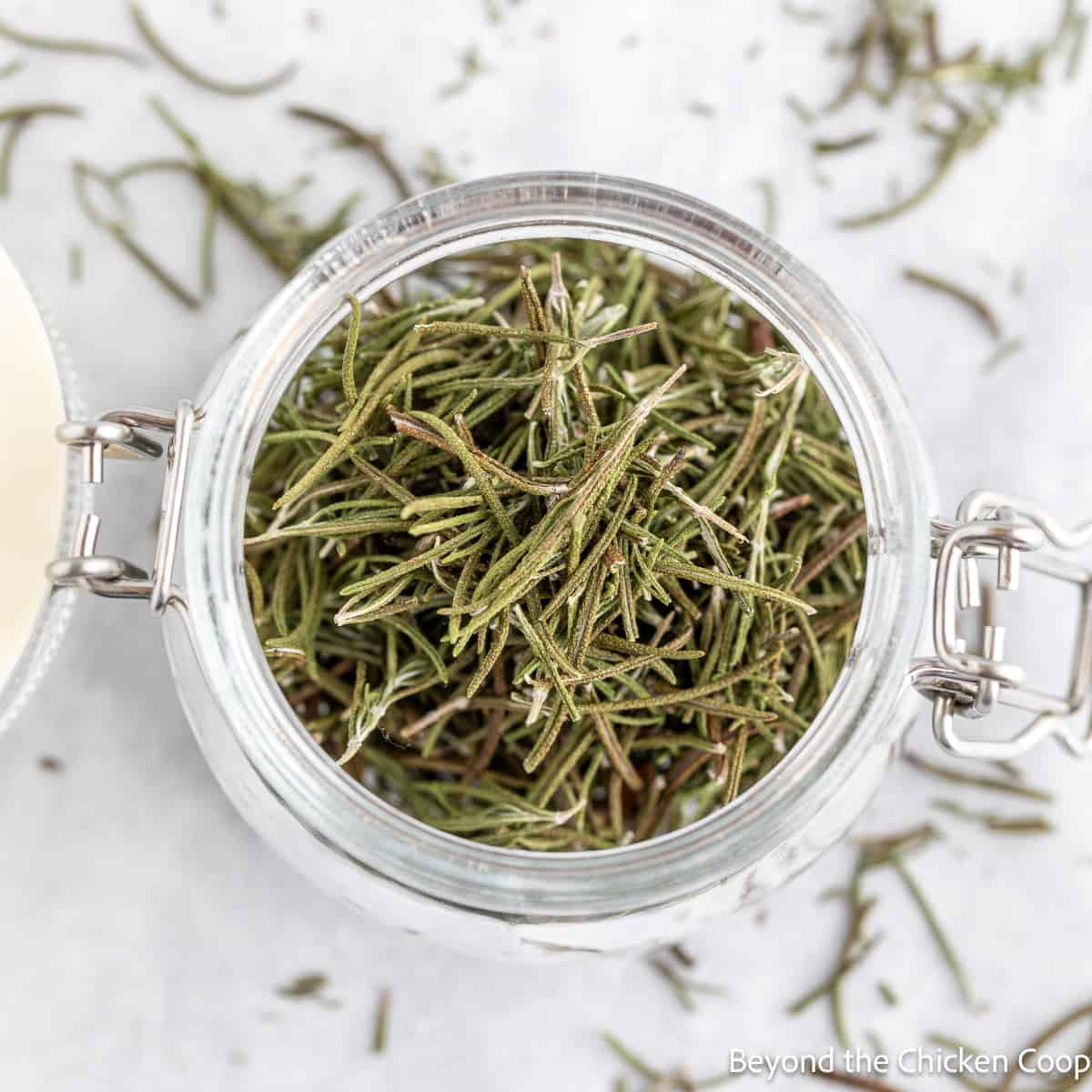 A jar filled with dried rosemary leaves.
