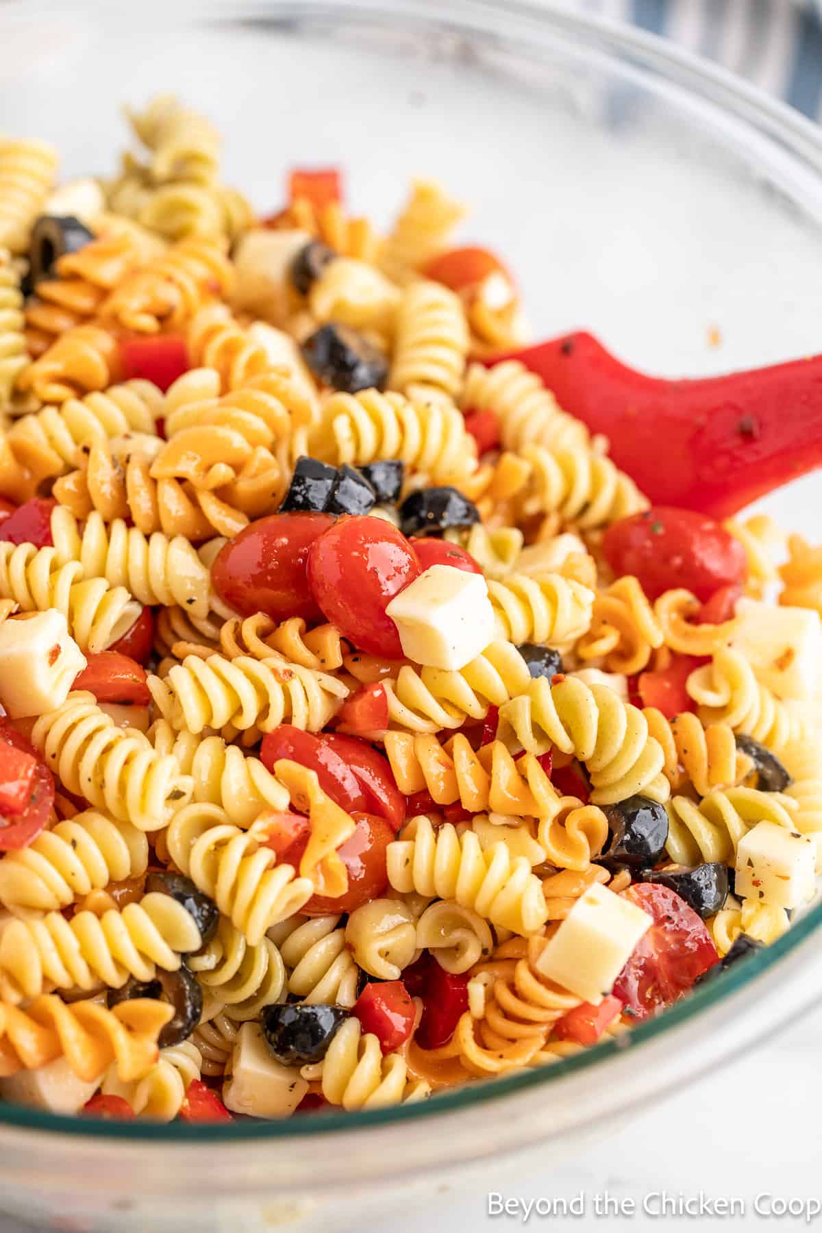 A large glass bowl filled with pasta salad. 