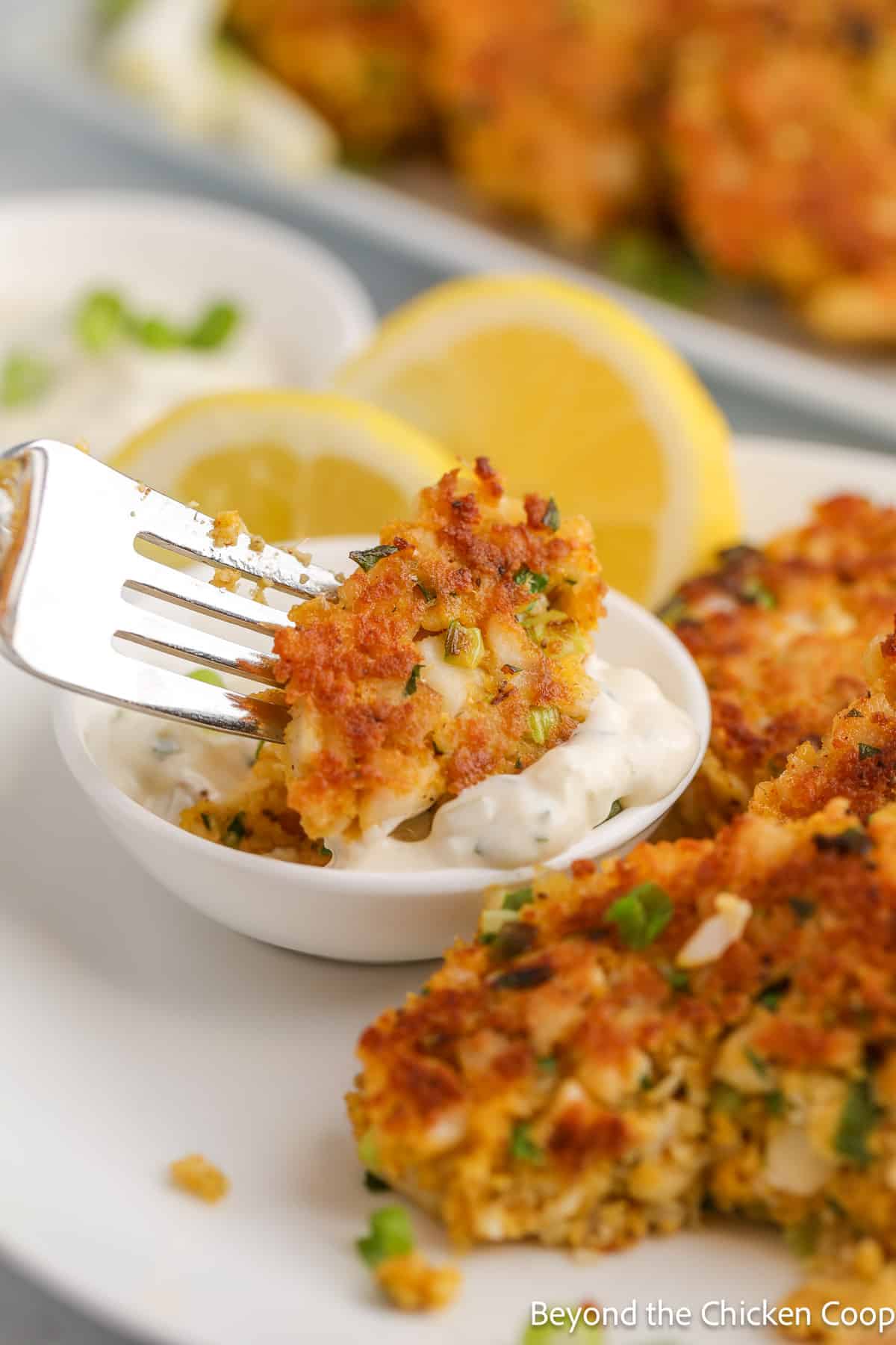 A fork with a bite of fish cake and tartar sauce. 