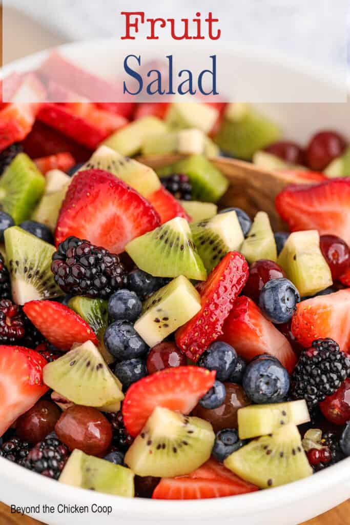 Berries, kiwi and grapes in a white bowl.