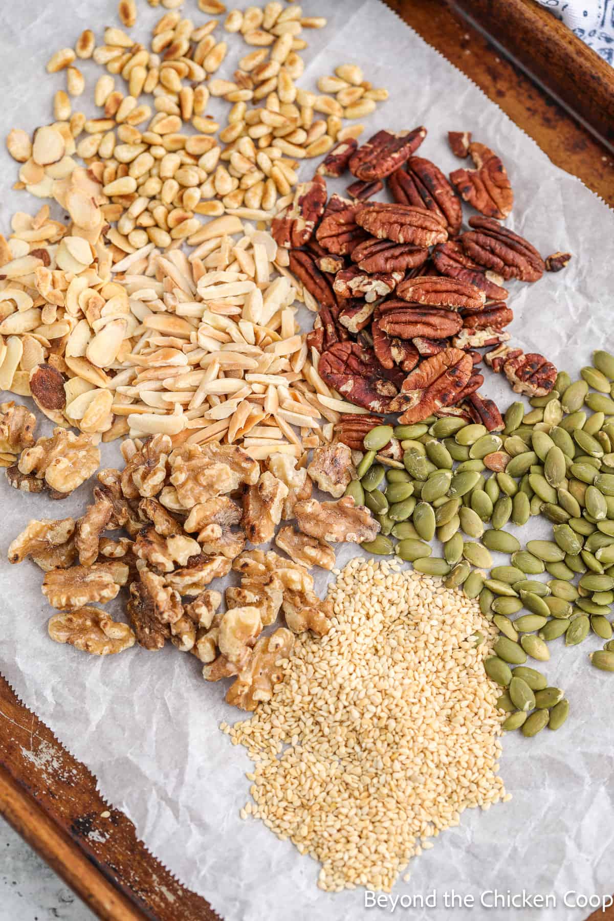 A variety of toasted nuts and seeds on a baking sheet. 