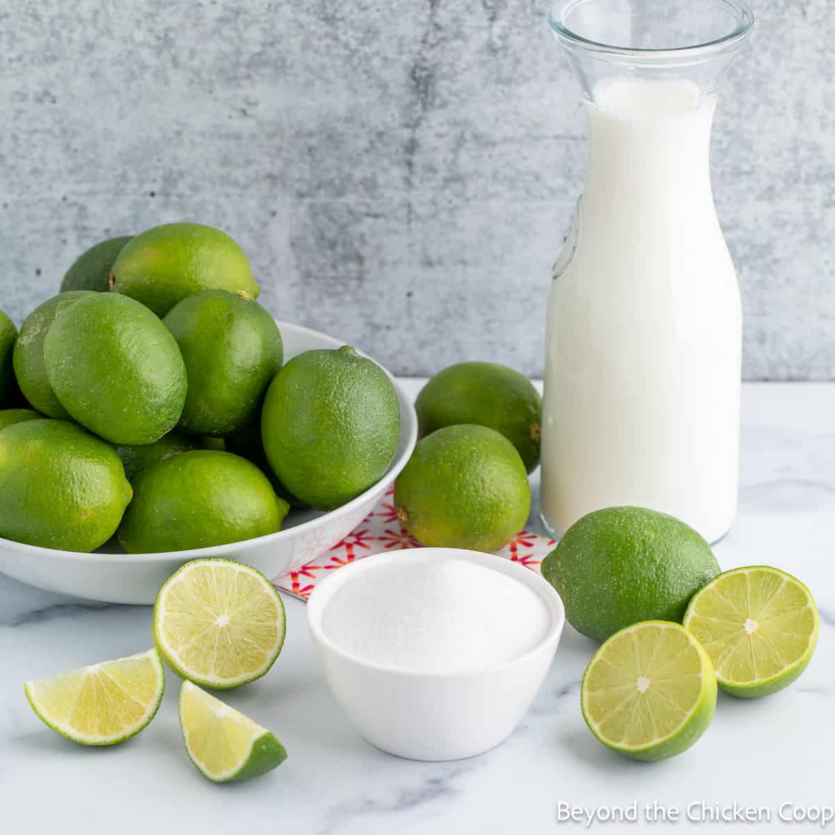 Fresh limes, a bowl of sugar and a carafe of milk. 