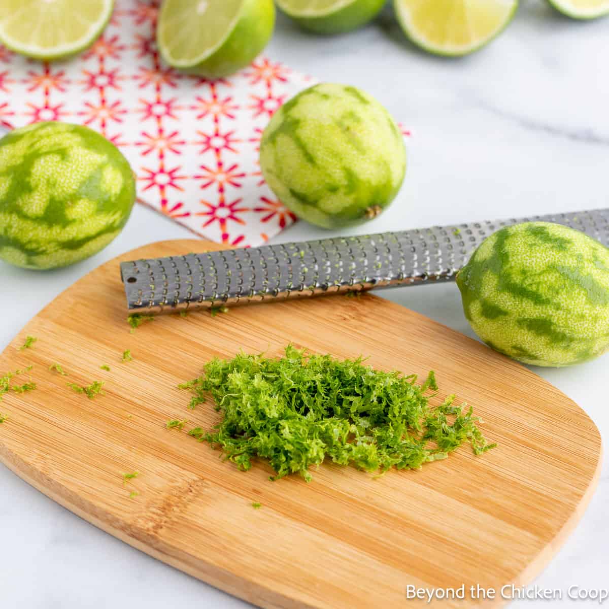 Zesting limes on a board.