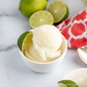 Scoops of sorbet in a bowl with a lime wedge.