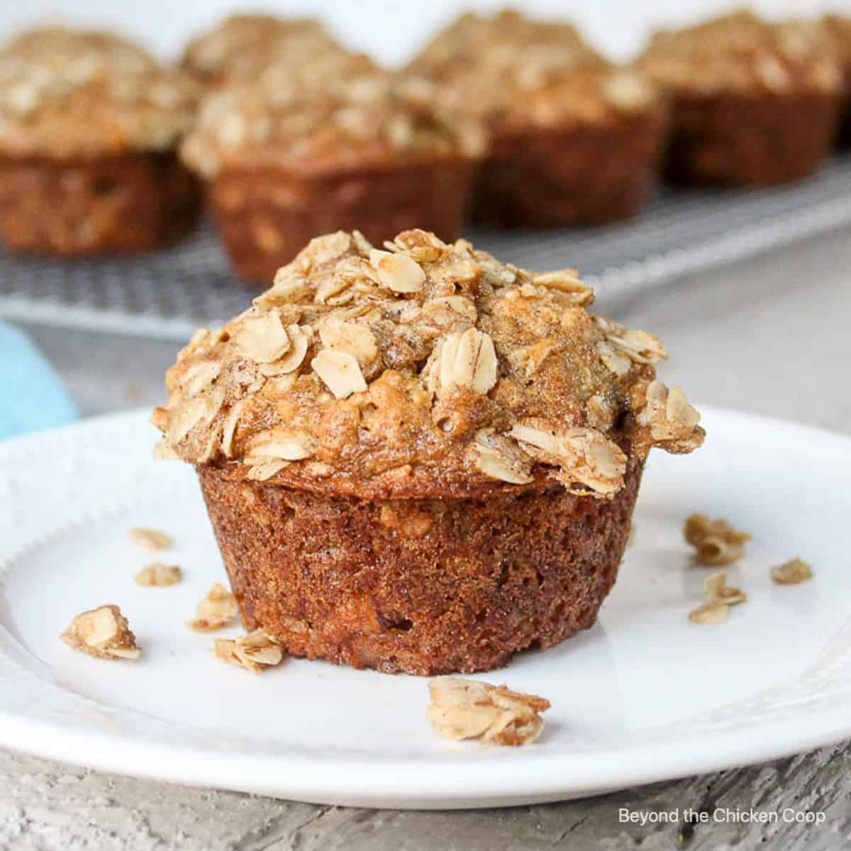 A single oatmeal banana muffin topped with a crumbly topping on a plate.