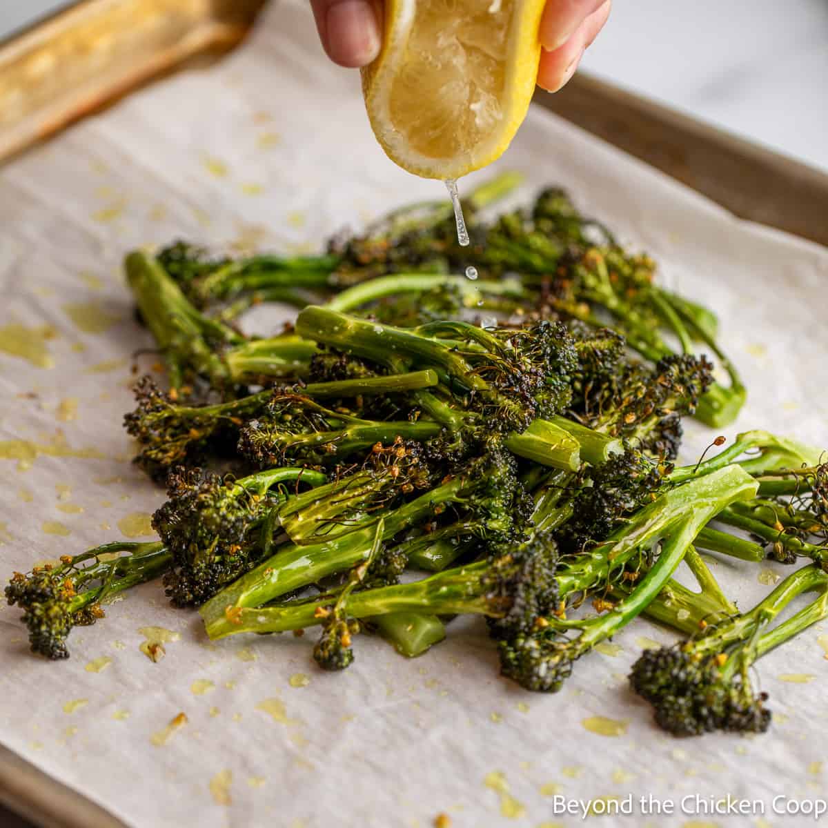 Lemon juice being squeezed over cooked broccoli. 