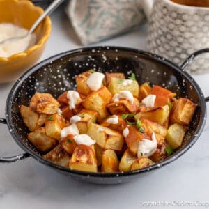 Cubed potatoes topped with a red and a white sauce.