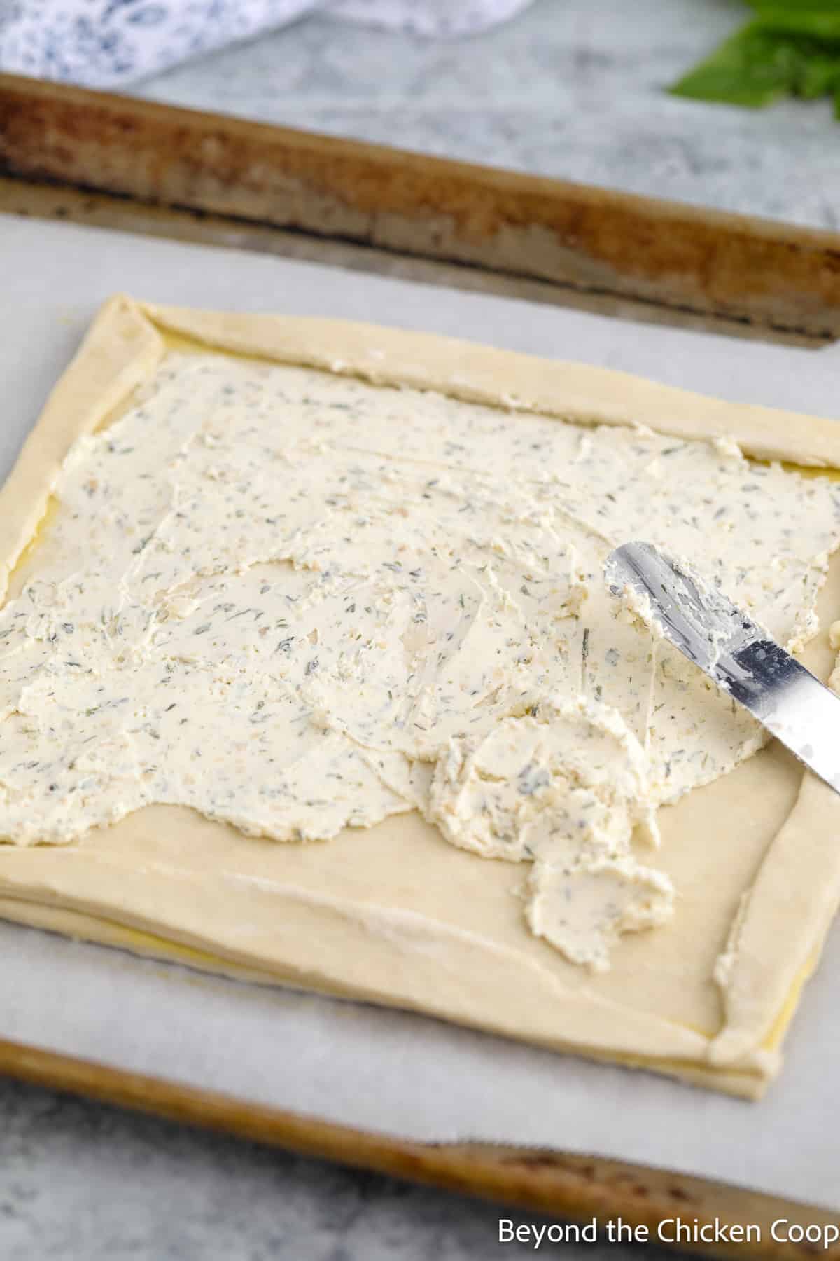 Spreading a soft cheese onto puff pastry. 