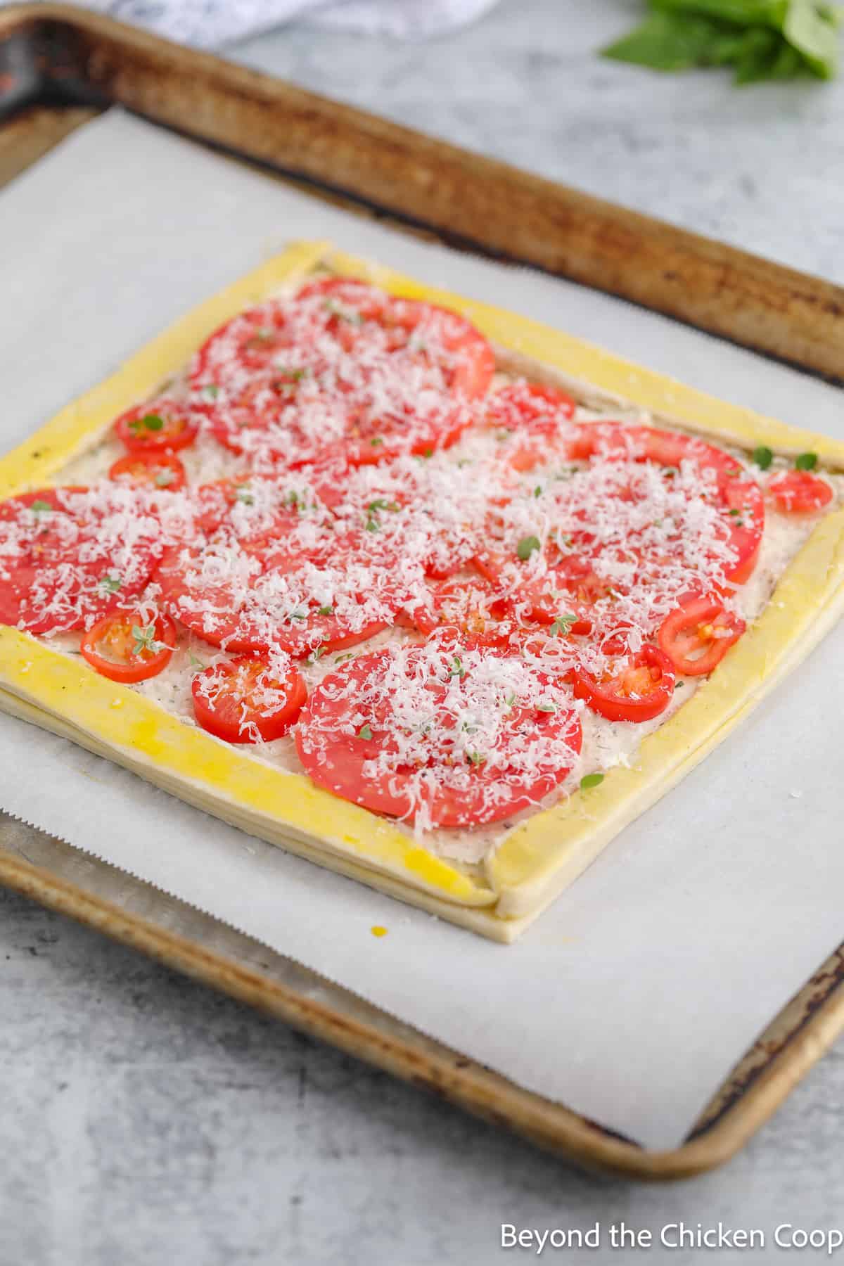 An unbaked tomato tart on a baking sheet. 