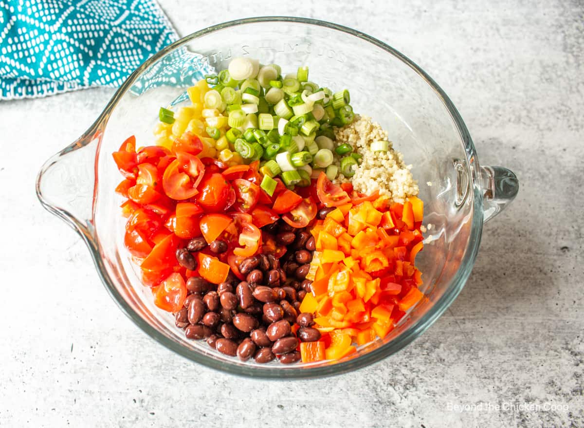 Chopped tomatoes, peppers, black beans and green onions in a glass bowl.